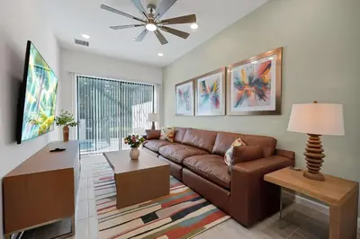 a living room with a brown couch and a ceiling fan at New 5BR Villa Near Disney I Resort Lazy River in Orlando