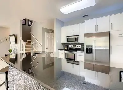 a kitchen with white cabinets and stainless steel appliances at Condomínio Encantada c/ Piscina & Vista ao Lago in Kissimmee