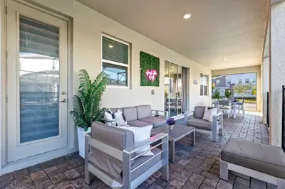 a porch with a couch and chairs and a table at Close to Disney! Pool, Spa, Game, & Movie Room! in Kissimmee