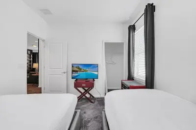 a white room with two beds and a television at Lakefront | Sleeps 18 | 8-Bed Villa w/ Pool & Epic in Kissimmee