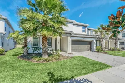 a palm tree in front of a house at Lakefront | Sleeps 18 | 8-Bed Villa w/ Pool & Epic in Kissimmee