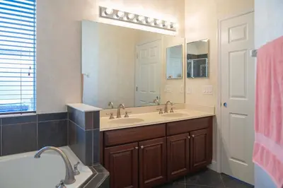 a bathroom with two sinks and a tub and a mirror at 5BR 4BA Pool Pool Table Near Disney in Kissimmee