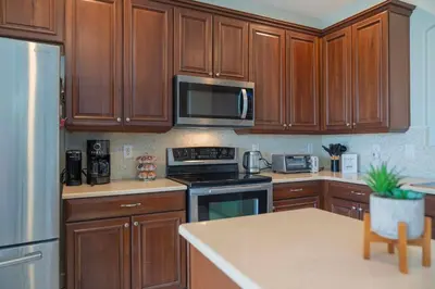 a kitchen with wooden cabinets and a stove top oven at 5BR 4BA Pool Pool Table Near Disney in Kissimmee