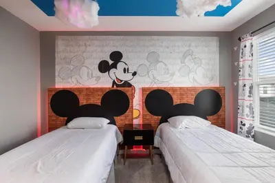 a bedroom with two beds with mickey mouse on the wall at Close to Disney! Pool/Spa/Game & Movie room! in Kissimmee