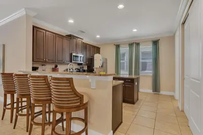 a kitchen with wooden cabinets and bar stools at 480 Lasso Dr. · 480 Villa - Large Luxury 7BD Home - SpaPool in Orlando