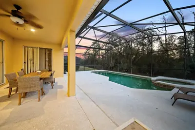 a patio with a table and chairs and a swimming pool at Cozy Villa 08 BedroomsPoolGame Room in Kissimmee