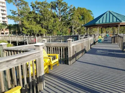 a wooden boardwalk with yellow benches and a gazebo at Blue Heron Beach Resort Tower 12 FL 1204 Fully Furnished in Orlando