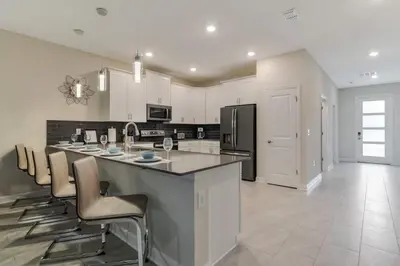 a kitchen with a large island with bar chairs at Your Beautiful Hideaway 9-Bedroom Luxury Villa in Kissimmee