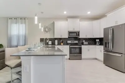 a kitchen with white cabinets and stainless steel appliances at Your Beautiful Hideaway 9-Bedroom Luxury Villa in Kissimmee
