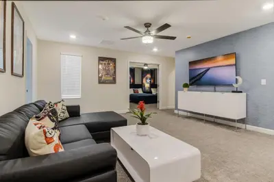 a living room with a black couch and a tv at Your Beautiful Hideaway 9-Bedroom Luxury Villa in Kissimmee