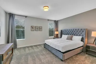 a bedroom with a bed and a desk and windows at Casa 6Q c/ Piscina & Sala de Jogos — Storey Lake in Kissimmee