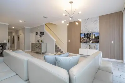 a living room with a white couch and a staircase at Townhome 5Q c/ Piscina – 8mi da Disney in Kissimmee