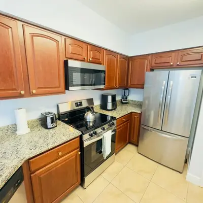 a kitchen with wooden cabinets and stainless steel appliances at Your Epic Disney Getaway Spacious Home 3BD 3BA in Orlando