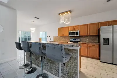 a kitchen with a island with bar stools and a refrigerator at Famous 5 Star Home in Kissimmee with Game Room in Kissimmee