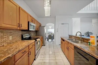 a large kitchen with wooden cabinets and a sink at Famous 5 Star Home in Kissimmee with Game Room in Kissimmee