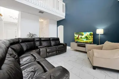 a living room with a leather couch and a television at Famous 5 Star Home in Kissimmee with Game Room in Kissimmee