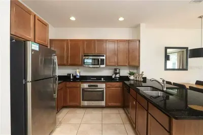 a kitchen with wooden cabinets and a stainless steel refrigerator at Casa 3Q no Regal Oaks Resort, Perto da Disney in Orlando