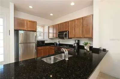 a kitchen with a stainless steel refrigerator and black counter tops at Casa 3Q no Regal Oaks Resort, Perto da Disney in Orlando