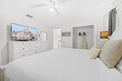 a white bedroom with a large bed and a flat screen tv at Casa c/ 4Q no Storey Lake Resort c/ Piscina in Kissimmee