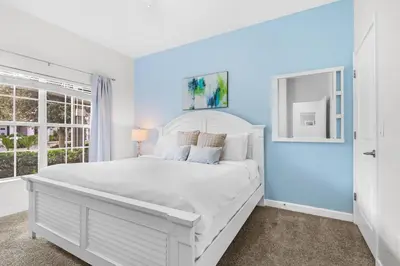 a white bed in a room with a blue wall at Casa c/ 4Q no Storey Lake Resort c/ Piscina in Kissimmee