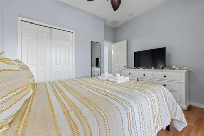 a white bedroom with a bed and a tv at Water View Pool Home Near Disney in Kissimmee