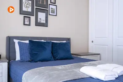 a bed with blue pillows and pictures on the wall at 7547 NEW 5 minutes from Disney 5BD 5BH 15P in Orlando