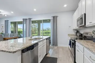 a kitchen with white cabinets and granite counter tops at 381 Fantastic Home Near Disney 5BD 5BT 14P in Orlando