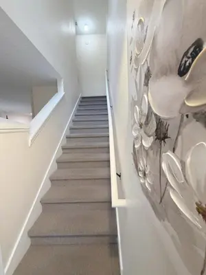 a stairway with white walls and a staircase with a painting at The Family Den in Kissimmee