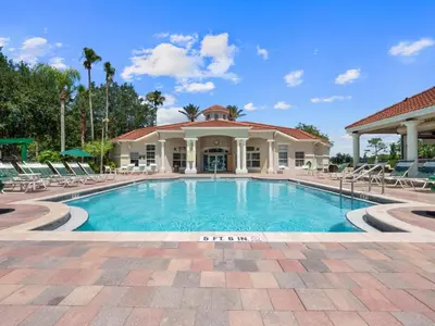 a swimming pool with chairs and a building at Sun Key Getaway in Kissimmee