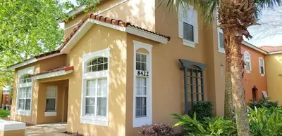 a yellow house with white windows and a palm tree at The Beauty at Emerald Island in Kissimmee