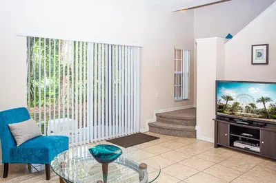 a living room with a tv and a blue chair at Bella Vista at Emerald Island in Kissimmee