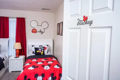 a bedroom with a bed with a red blanket with mickeys on it at Bella Vista at Emerald Island in Kissimmee