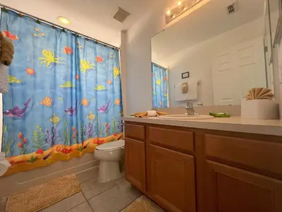 a bathroom with a blue shower curtain and a toilet at La Isla at Paradise by PropertyChekker! in Kissimmee