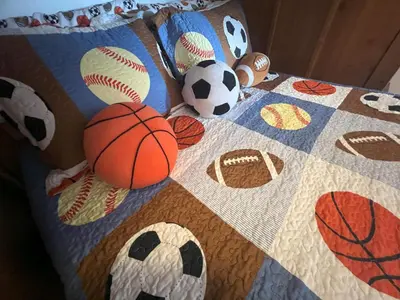 a quilt with basketballs and balls on a bed at La Isla at Paradise by PropertyChekker! in Kissimmee