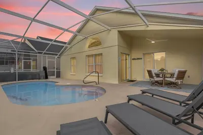 a house with a swimming pool with a table and chairs at Sunny Side Up in Orlando