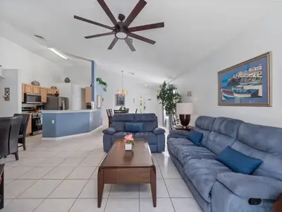 a living room with blue couches and a ceiling fan at Oasis Key Retreat by PropertyChekker! in Kissimmee