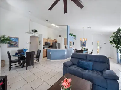 a living room with a blue couch and a kitchen at Oasis Key Retreat by PropertyChekker! in Kissimmee