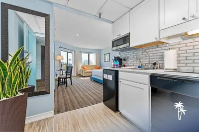 a kitchen with white cabinets and a living room at Superior Central Condo with Balcony 7 Min to Universal in Orlando