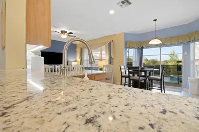 a kitchen with a granite counter top and a dining room at Windsor Hills Fun 6BR Villa Pool Spa By Disney in Orlando