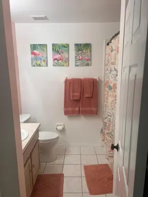 a bathroom with a toilet and three paintings on the wall at Woodland Yard in Kissimmee