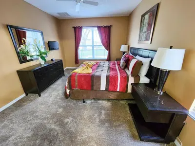a bedroom with a bed and a table and a lamp at Spacious 7BR Retreat w Pool & Jacuzzi V#202 in Kissimmee