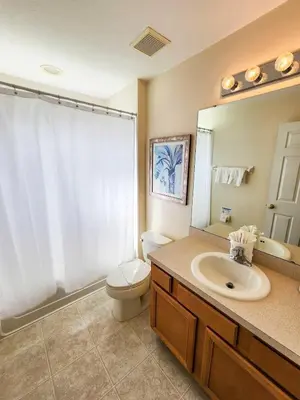 a bathroom with a sink and a toilet and a mirror at Spacious 7BR Retreat w Pool & Jacuzzi V#202 in Kissimmee
