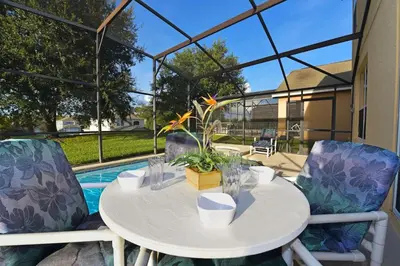a white table with a plant on it next to a pool at Spacious 7BR Retreat w Pool & Jacuzzi V#202 in Kissimmee
