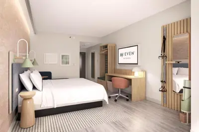 a bedroom with a white bed and a desk with a chair at EVEN Hotel Orlando Universal Blvd by IHG in Orlando