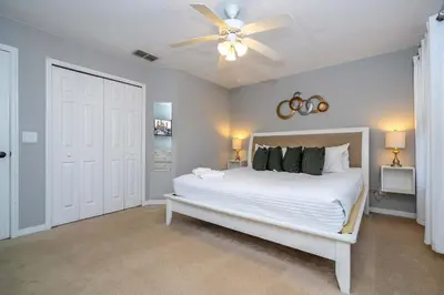 a bedroom with a white bed with a ceiling fan at Stylish 4BR Townhome Private Pool BBQ & Near Disney in Kissimmee