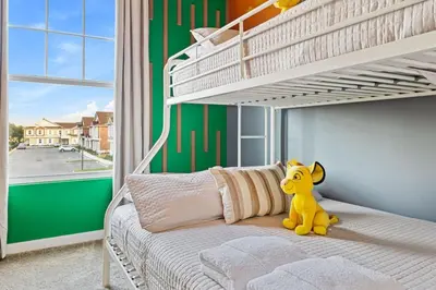 a yellow stuffed animal sitting on a bed in a bedroom at 5 Suites Sleeps 14 Lion King Mickey Theme in Orlando