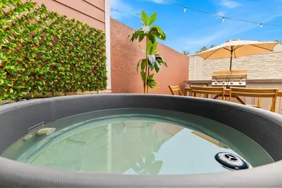 a hot tub in a backyard with an umbrella at 5 Suites Sleeps 14 Lion King Mickey Theme in Orlando