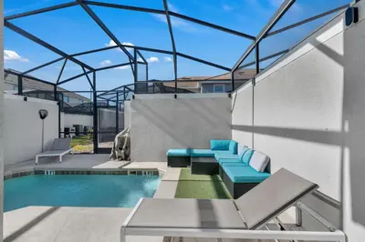 a patio with a swimming pool and blue lounge chairs at Kingdoms and Galaxies Luxury Villa in Kissimmee