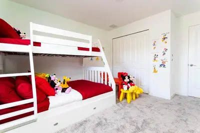 a bedroom with a white bunk bed with red pillows at Townhome 4Q Storey Lake - Piscina & Temas in Kissimmee