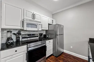 a kitchen with white cabinets and a stainless steel refrigerator at Near Disney! Kissimmee Home for 12 w/ Pool Access! in Kissimmee